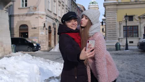 sisters couple bloggers taking selfie, making video conferencing call on mobile phone on city street