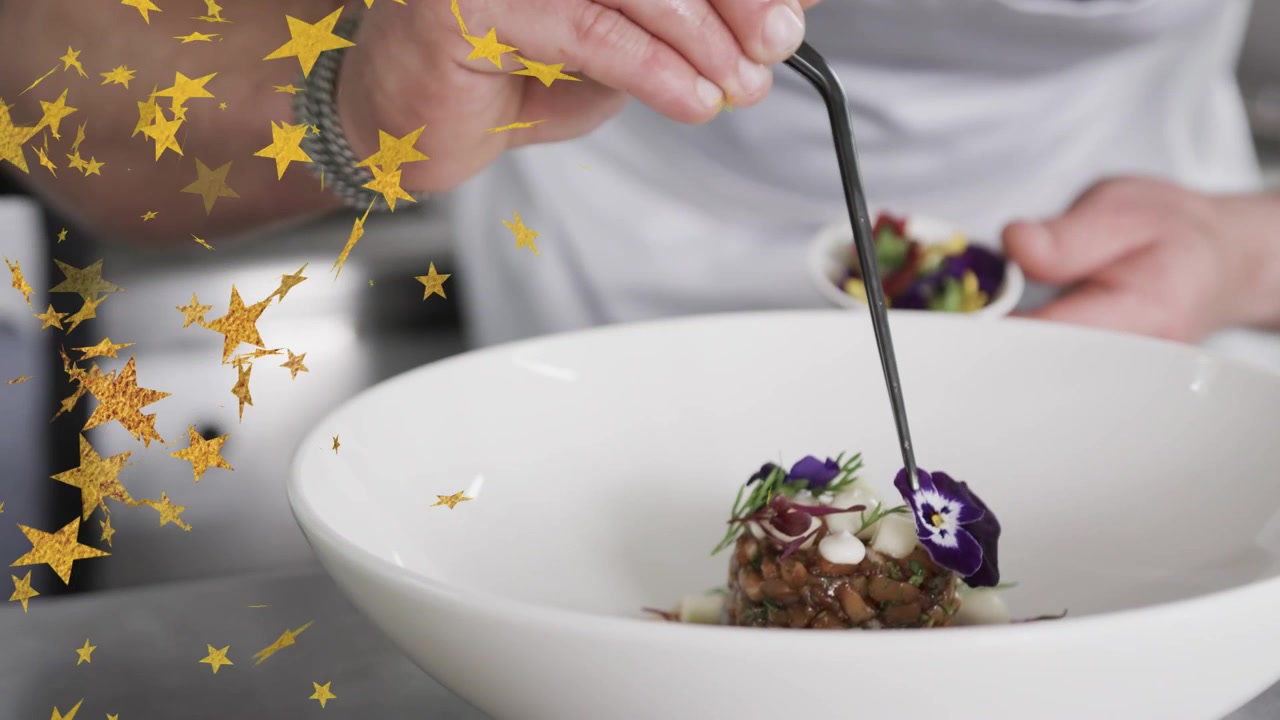 Koch nimmt Stiefmütterchen aus Ramekin und platziert Garnitur auf Gericht zum Anrichten, mit goldenem Stern links überlagert.