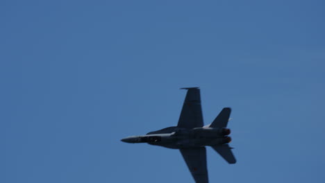 military jet fighter performing a sharp left turn against clear blue sky