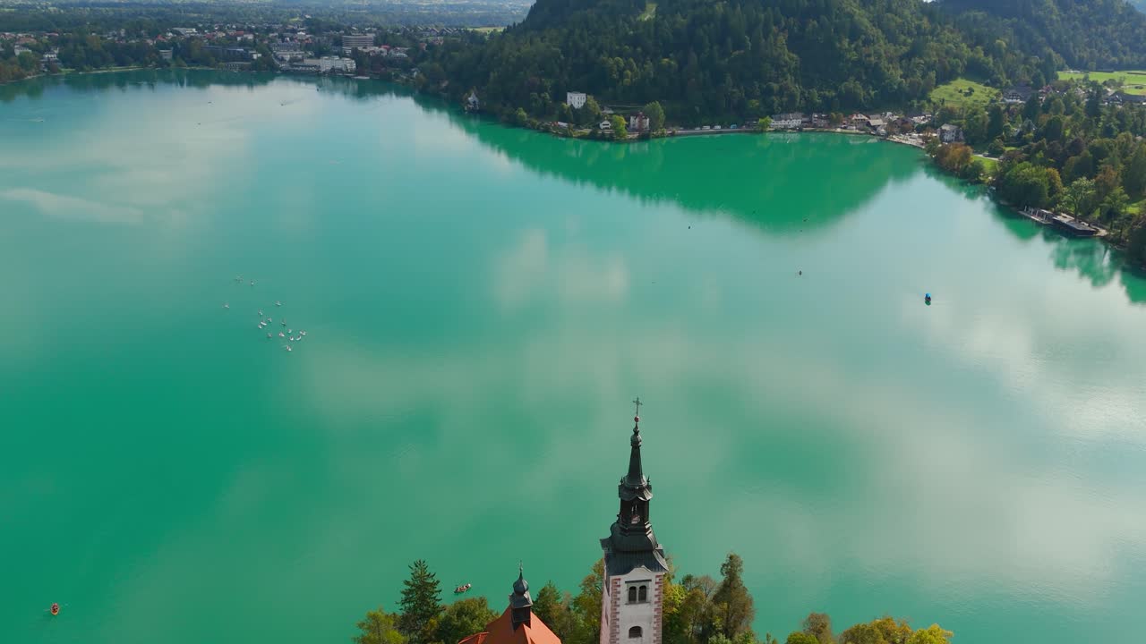 Aerial establishing of Bled Island and Church of the Assumption of St. Mary, glistening green lake water