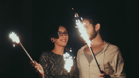 joven pareja hipster divirtiéndose con fuegos artificiales en manos de