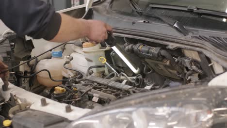 auto mechanic working on car engine in mechanics garage. repair service.