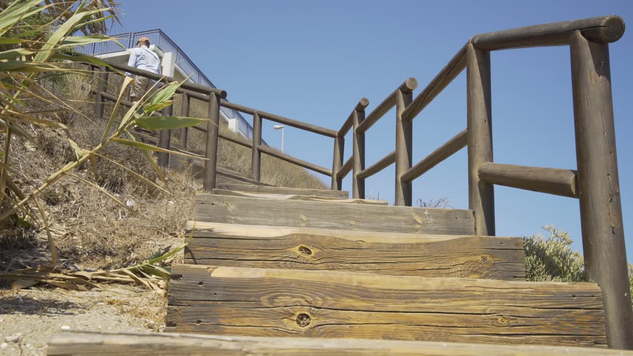 Man Walking up the Wooden steps of the beach at Cala de Mijas on the Costa Del Sol in Southern Spain.