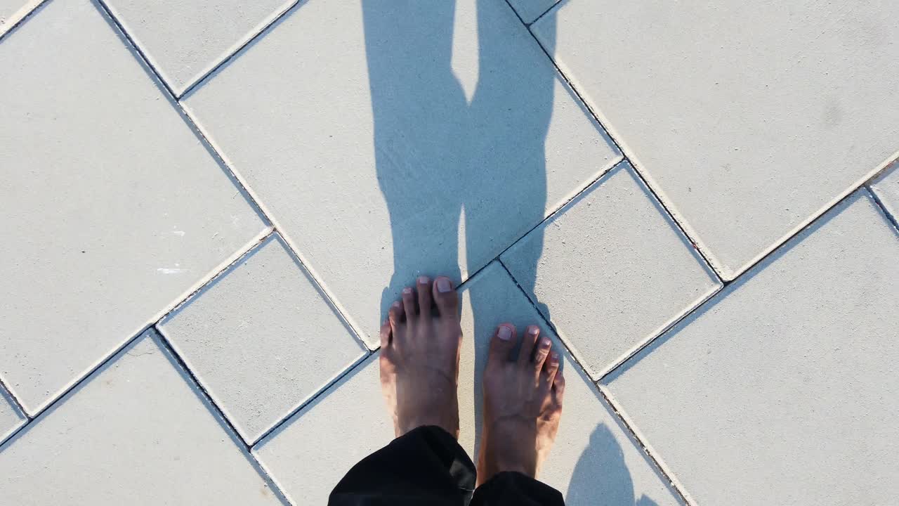 a man is walking barefooted on a tiled road