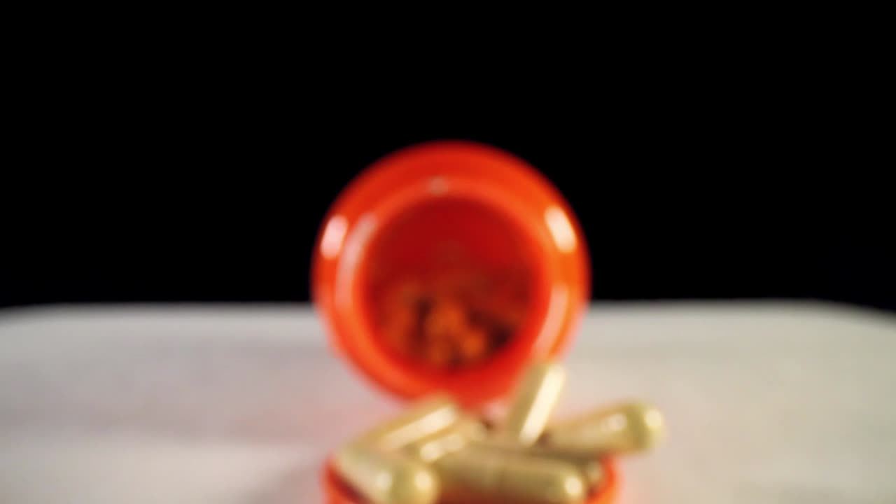 moviéndose más allá de la tapa, empujando lentamente hacia un frasco de píldoras de suplemento naranja