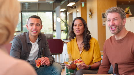 en una reunión informal del personal en la oficina con pizza para llevar haciendo un brindis con bebidas