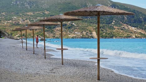 hombre de pie junto a la orilla de la idílica y tranquila playa de agia kyriaki en kefalonia, grecia - tiro ancho