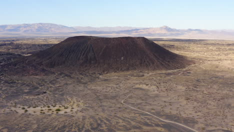 high altitude tilt down view of volcanic amboy crater and the dirt road leading away