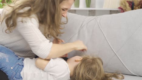 mamá divirtiéndose con su hija cosquilleándola y haciéndola reír.