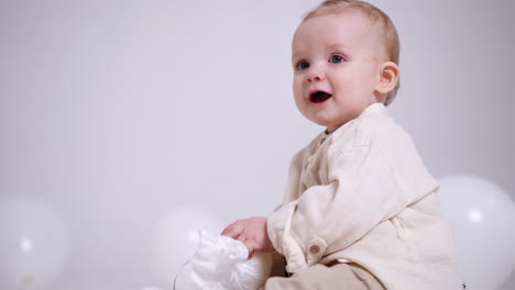lovely caucasian child is given a bundle with a string. adorable baby turns the bundle in hands playing with it. white backdrop.