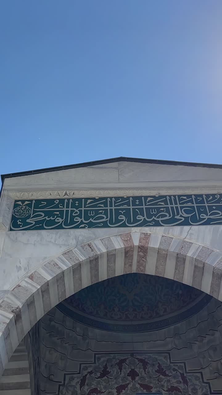 Push in tilt up reveals Suleymaniye Mosque entrance sign at midday