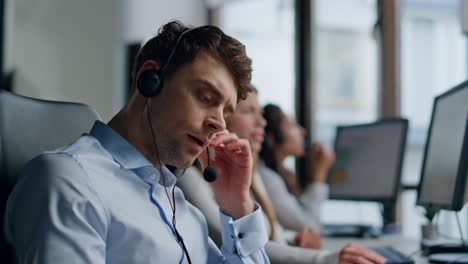 serious agent talking headset in customer support office closeup. tired man work