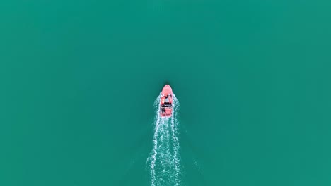 Birdseye-view-of-motorboat-driving-through-green-water-with-small-wake