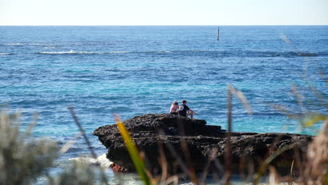 Dos-Personas-Románticamente-Sobre-Rocas-Junto-Al-Borde-Del-Agua