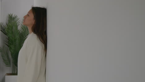 stressed or anxious woman suffering with depression and anxiety leaning against wall at home