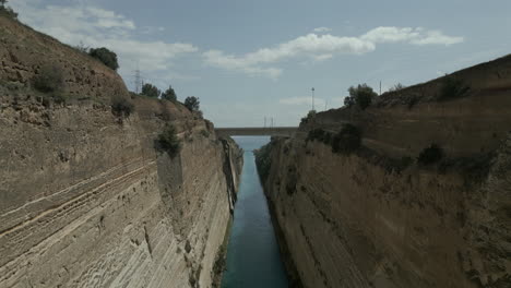 drone footage in corinth, greece, flying under a bridge in the corinth canal with the sea in the background