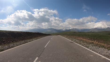 point of view driving a car on a road. mount elbrus is visible in the background.