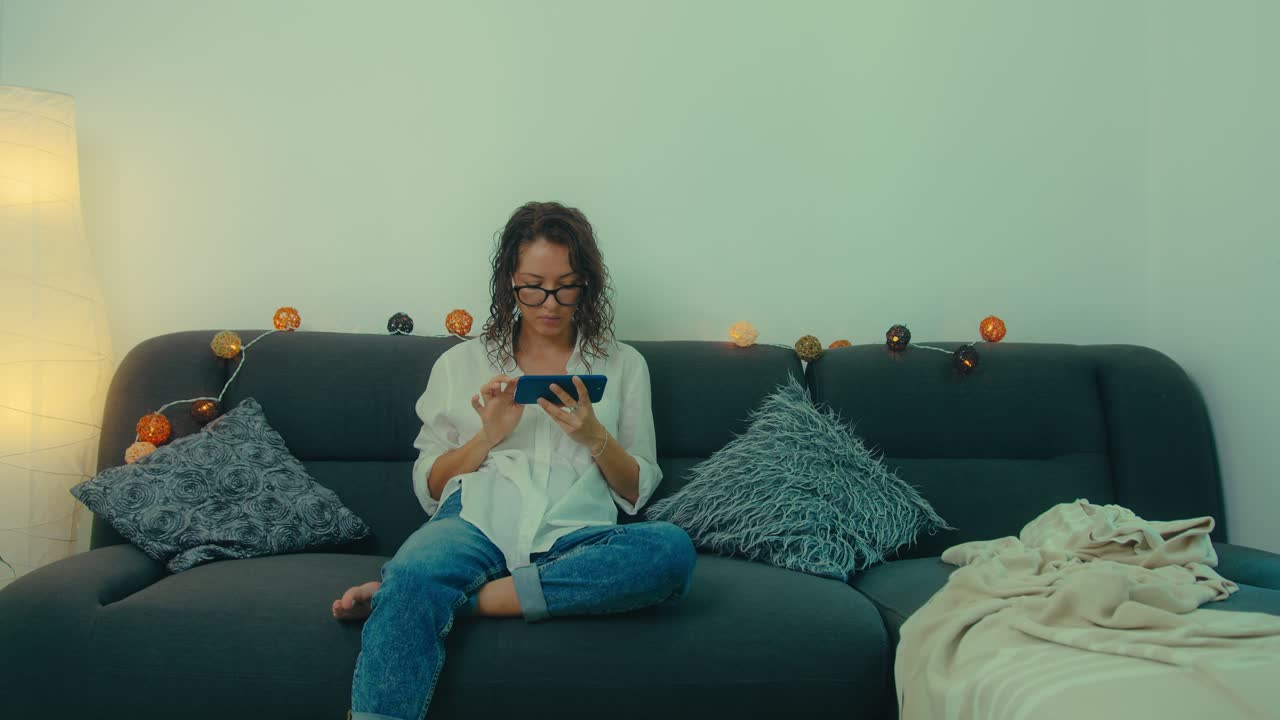 Woman using smartphone on a couch at home