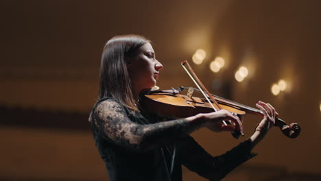 brunette woman is playing violin in philharmonic hall female musician in symphonic orchestra