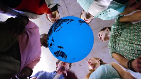 Animation-of-blue-globe-rotating-over-happy-diverse-colleagues-stacking-hands-at-casual-office