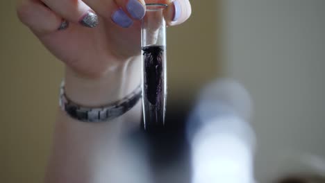 person holding a test tube with a dark purple liquid