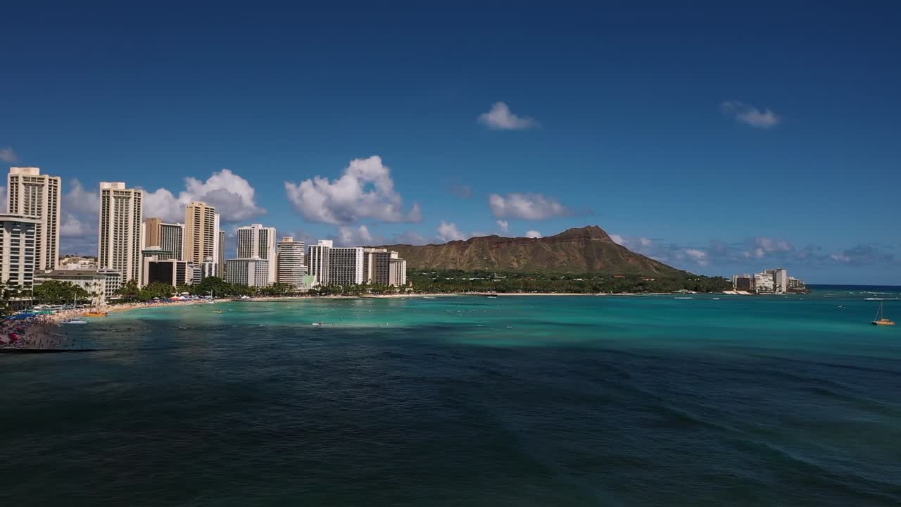 Vista aerea da drone che mostra lo skyline di Waikiki Beach con il cratere Diamond Head, l'acqua turchese dell'oceano e gli alti edifici dei resort sotto un cielo azzurro limpido a Honolulu, sull'isola di Oahu, Hawaii