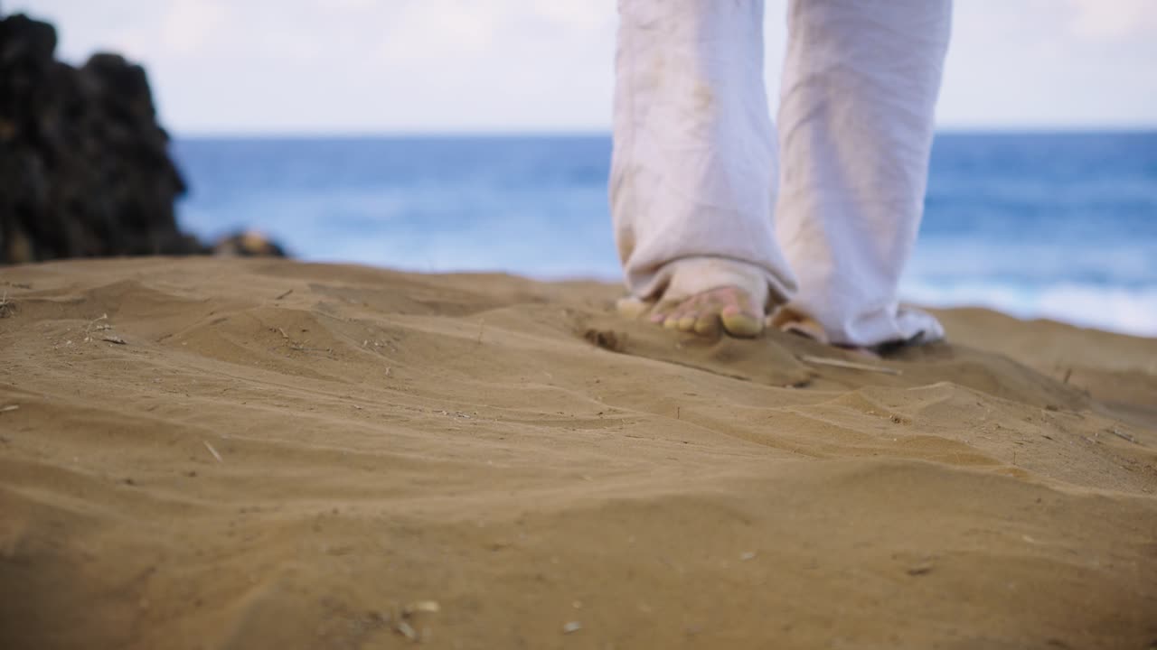 Close-up of bare feet pressing gently into smooth golden sand with the ocean in the background, capturing a peaceful moment of grounding, mindfulness, and connection to nature