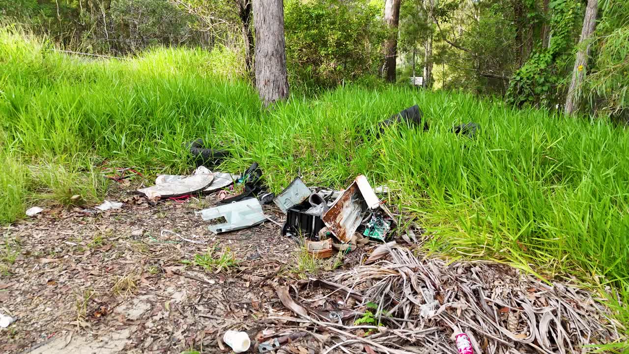 A sequence showing trash accumulation in a natural setting, highlighting pollution issues. Daylight illuminates the scene, emphasizing environmental neglect