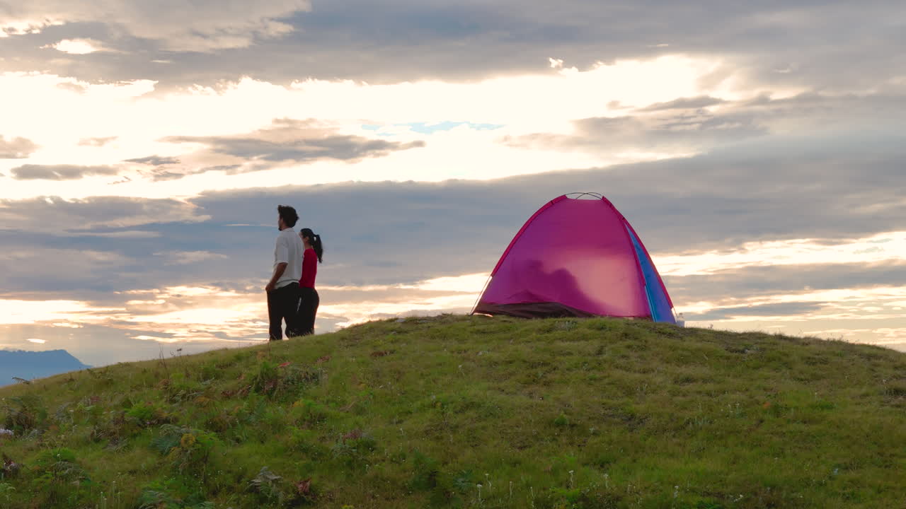 두 사람은 네팔 도라카의 세일룬에서 해가 뜨는 것을 목격하기 위해 텐트 밖으로 나와 산을 배경으로 푸른 하늘 아래 천상의 자연을 즐기며 울창한 초록색에서 산불 에서 따뜻하게 산책합니다.
