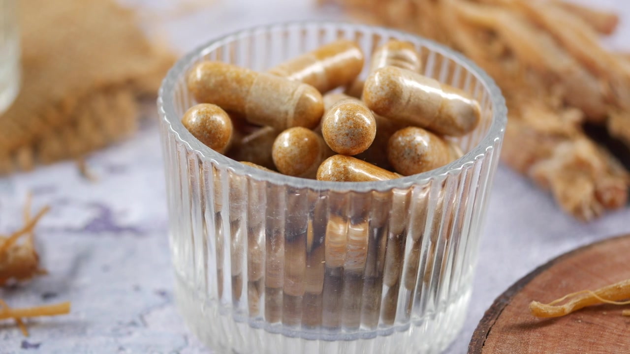 Capsule di integratore erboristico in un bicchiere di vetro