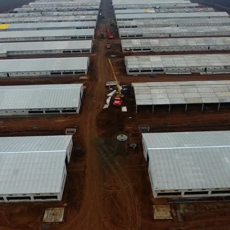 modern industrial buildings on brown field. new factory built in nature. roofs of warehouses. camera rising. aerial view.