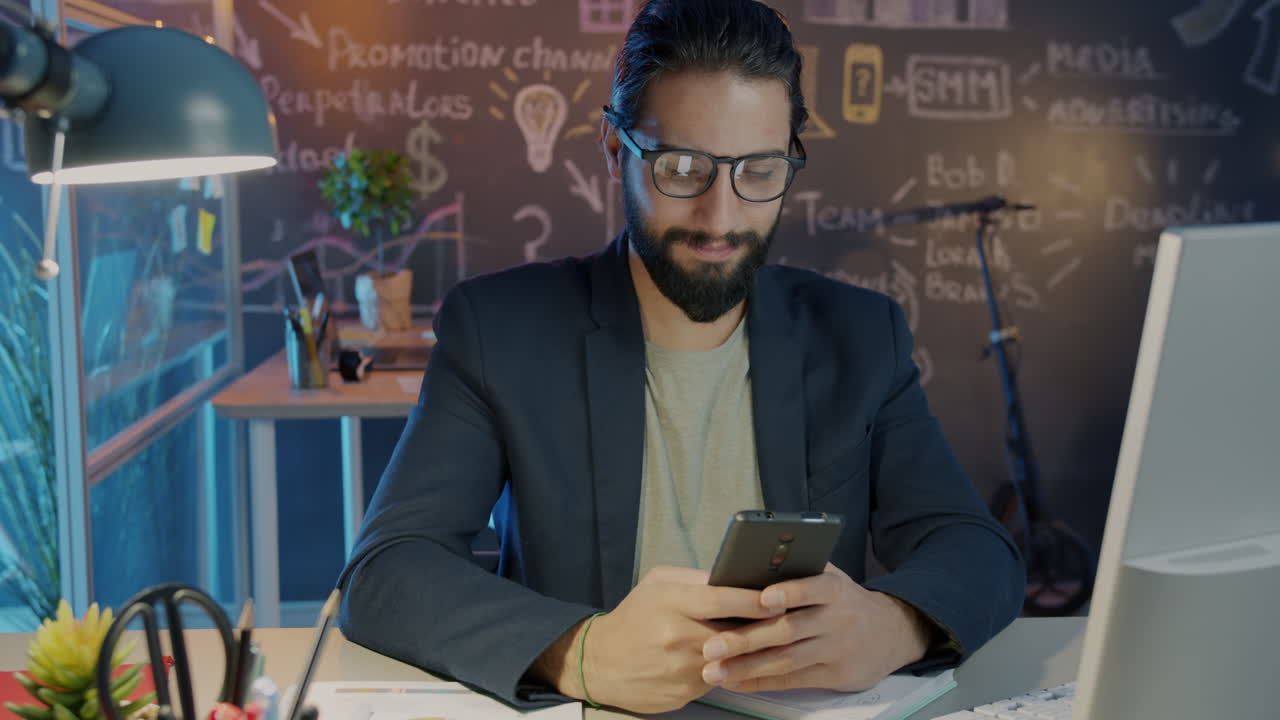 Businessman Checking Smartphone in Modern Office at Night