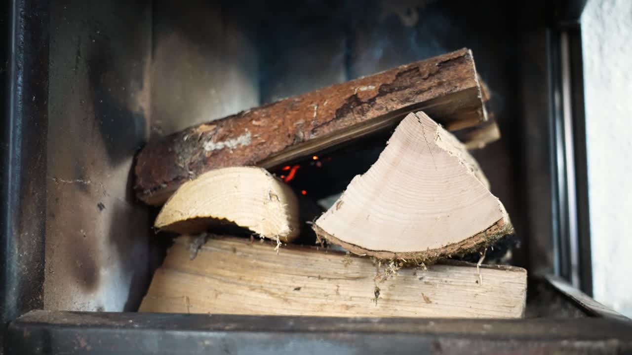 An attempt to light a fireplace has failed. The fresh firewood remains mostly unburned, with little or no flame visible. Indoor scene capturing an unsuccessful ignition moment