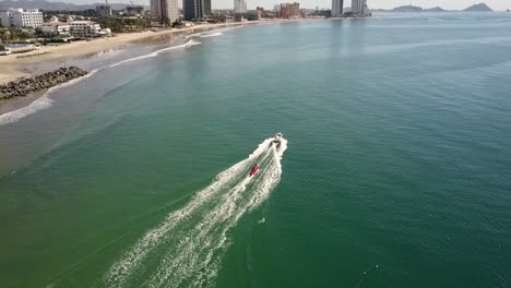 red tube water sled pulled by a speeding boat near the shore, mazatlan mexico