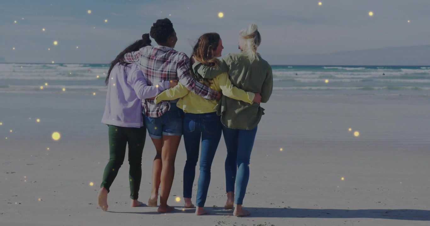 Gruppo di amici che camminano insieme sulla spiaggia con particelle di luce magiche