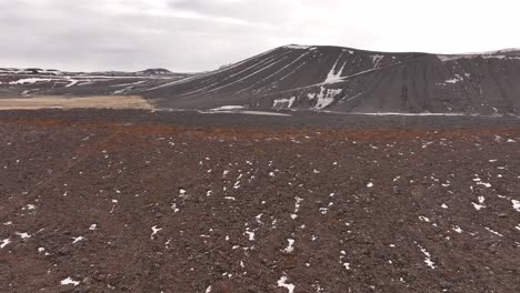 Hverfjall, a vast tephra crater in Iceland's Mývatn region, offers panoramic views of volcanic landscapes and pseudocraters. Rugged slopes provide a dramatic contrast to distant snow-dusted terrain.