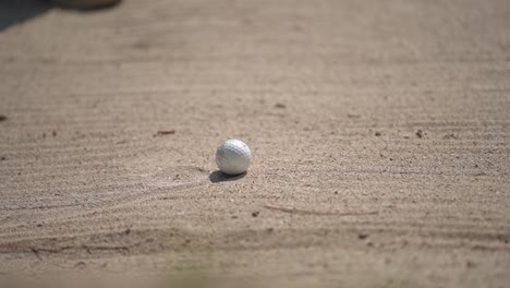 close up of golfer hitting the ball on a sandy course