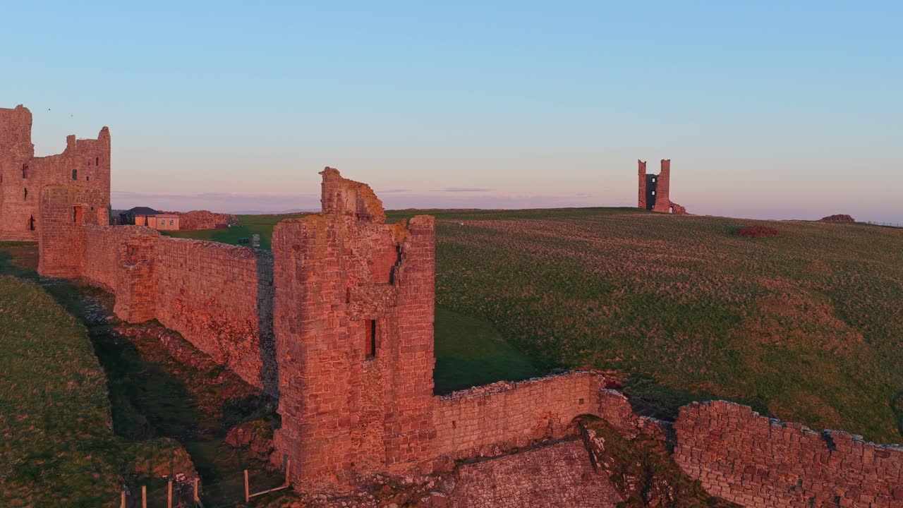 Solopgang i den gyldne time over ruinerne af Dunstanburgh Castle.