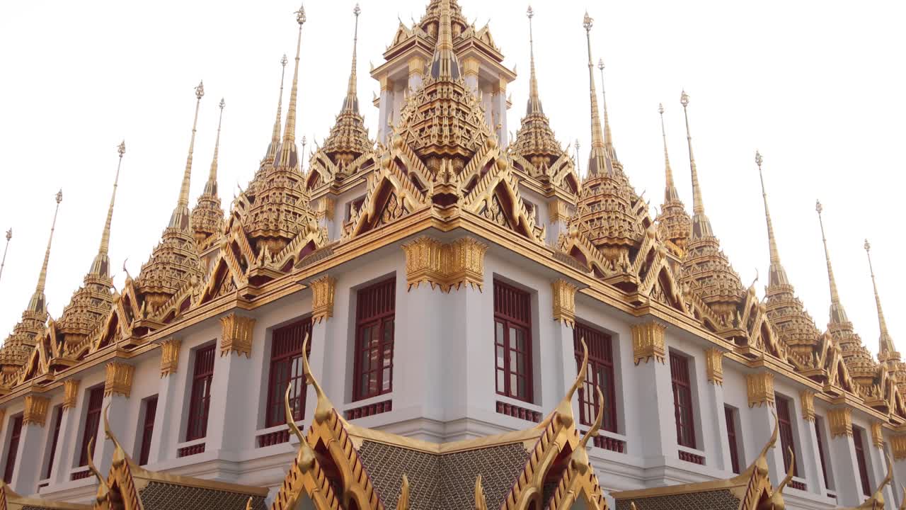 mirando hacia arriba a las altas agujas detalladas de la pagoda dorada en un complejo de templos budistas en el casco antiguo de rattanakosin de bangkok, tailandia