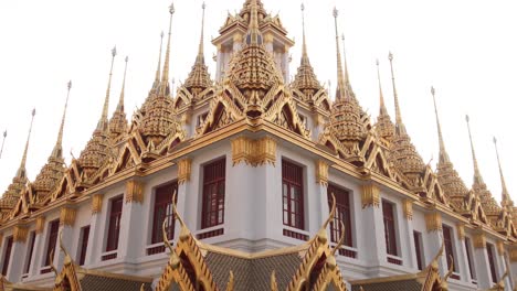 looking up at towering detailed golden pagoda spires in a buddhist temple complex in the rattanakosin old town of bangkok, thailand