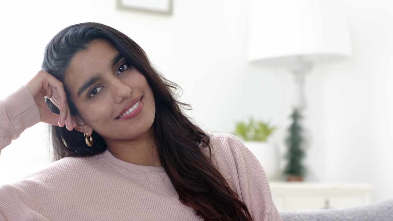 Smiling Indian woman relaxing at home, enjoying festive holiday atmosphere