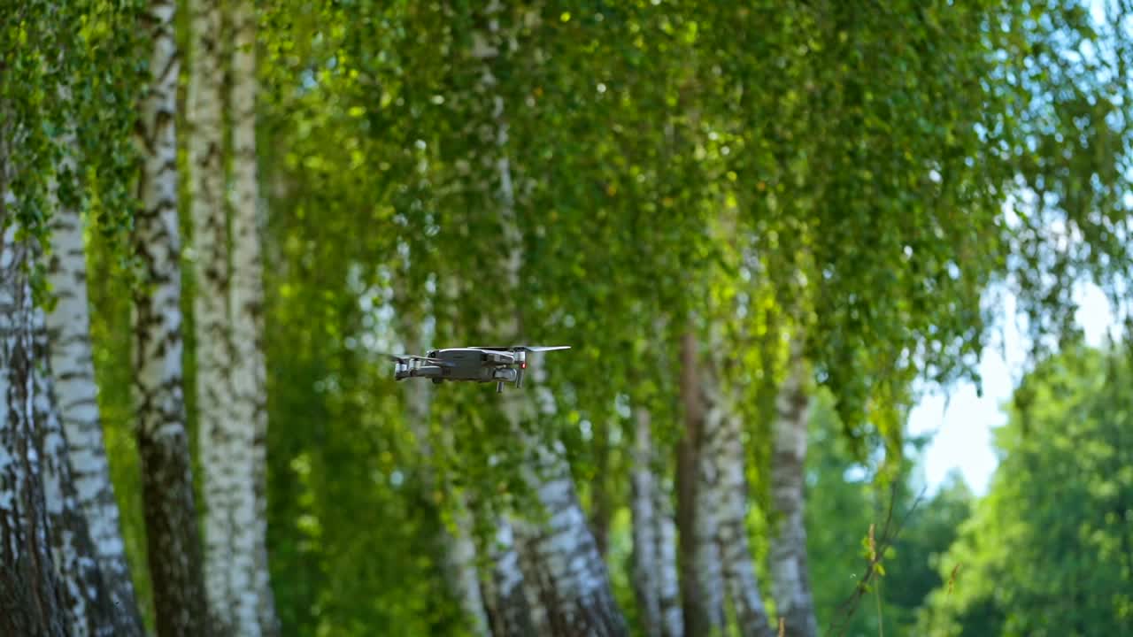Drone among nature in summer. Drone is flying on green birch trees background. Close-up.