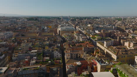 Volar-Hacia-Atrás-Por-Encima-De-Los-Edificios-En-La-Ciudad.-Imágenes-Panorámicas-Aéreas-Del-Casco-Antiguo,-Majestuoso-Monumento-Vittoriano-En-La-Distancia.-Roma,-Italia