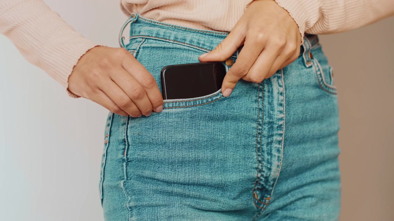 Donna che mette lo smartphone nella sua tasca dei jeans