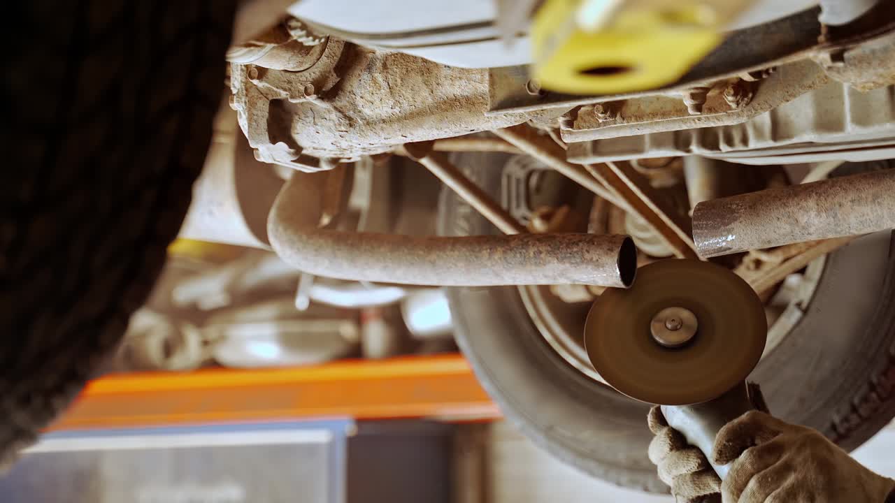 manos masculinas con guantes molen los bordes de la tubería de amortiguador aserrada con un molinillo angular