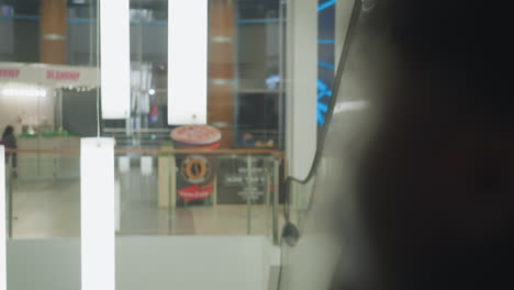 blurry shot of person standing, with focus on glowing white hanging light fixtures in modern space. background features shopping mall or commercial building with minimalistic design