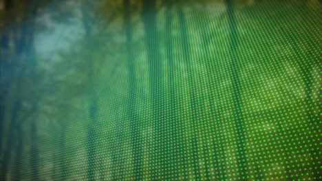 animation of blue to green rows of spots over trees in background