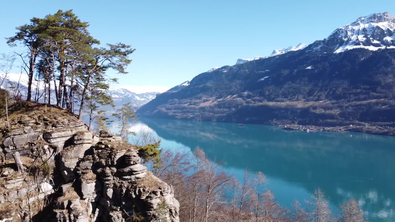 circle over a rock on a bright turquoise mountain lake, in which the swiss alps are reflected