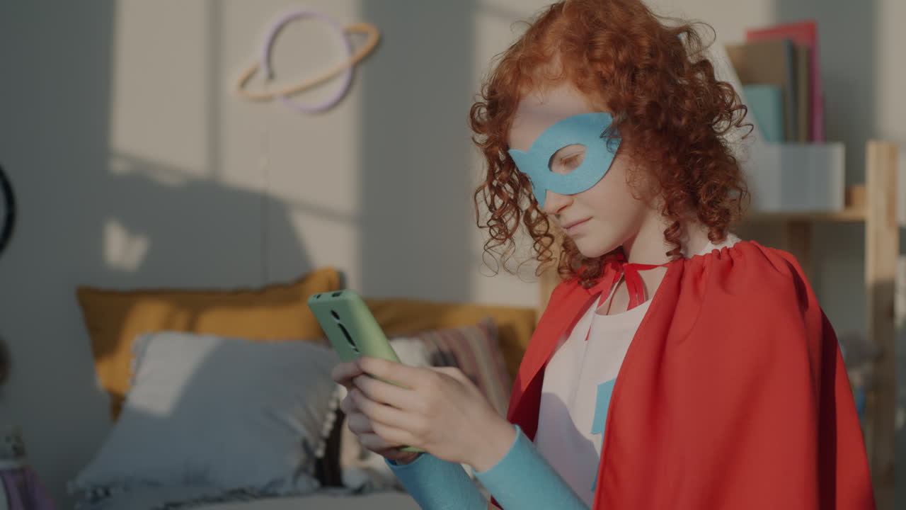 Young Superhero Girl Using Smartphone in Bedroom