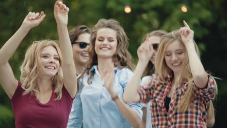 happy friends dancing, having fun and enjoying party outdoors.